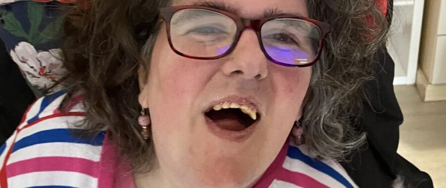 Clare, smiling in her wheelchair, with her animatronic cat Marmaduke